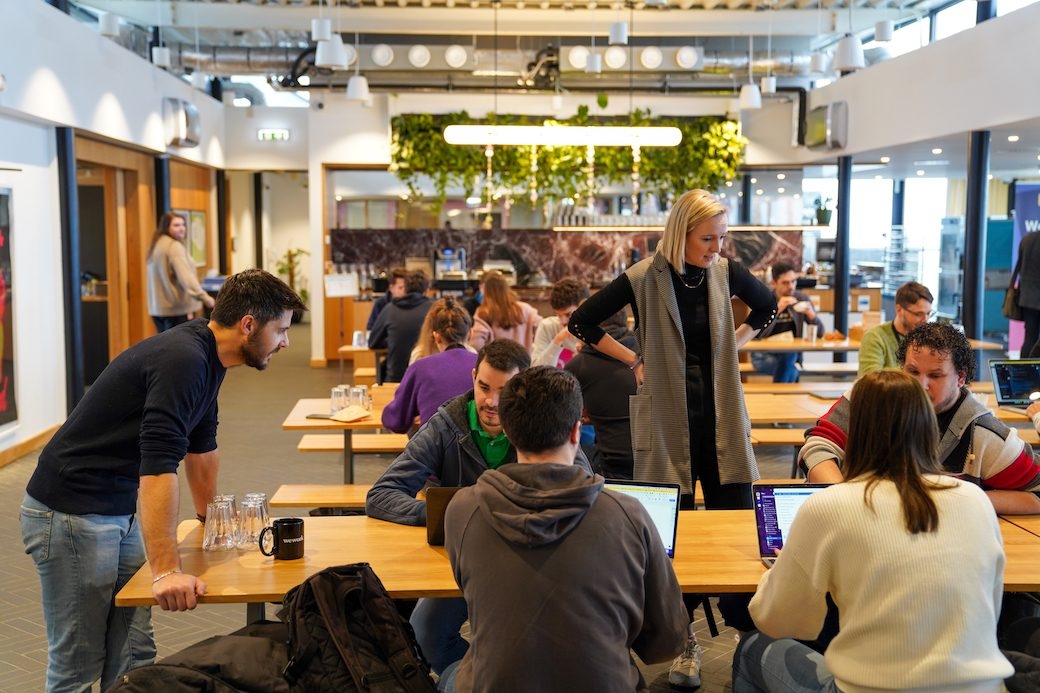 Miro employees fill an open-concept office space, collaborating together on a project